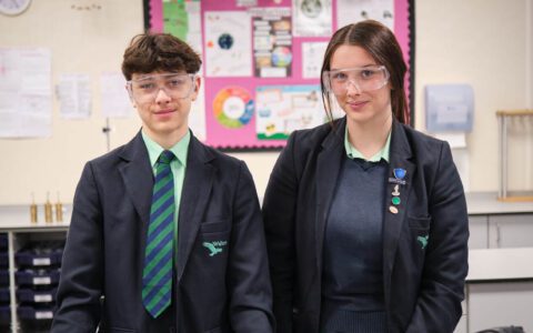 A boy and a girl smiling in a science classroom